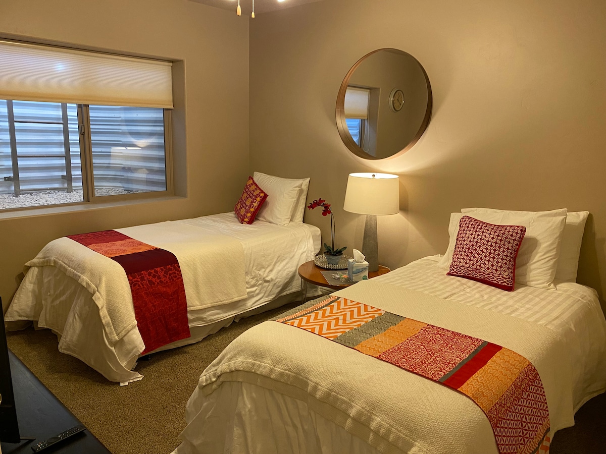 غرفة النوم رقم 4 في الطابق السفلي مع سريرين متماثلين وتلفزيون. بجوار حمام مع حوض وحوض استحمام/دش، مشترك مع غرفة النوم رقم 3.