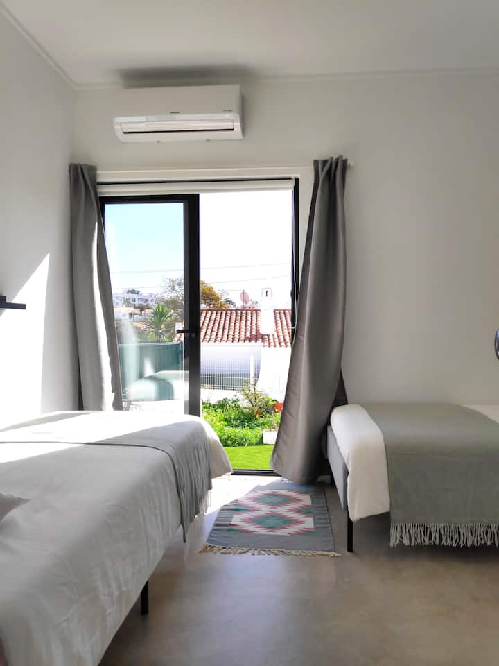 Tercer dormitorio (2 camas individuales, 90x200 cm cada una) con aire acondicionado y ventana al jardín. Todas las habitaciones tienen aire acondicionado tanto para calefacción como para refrigeración.