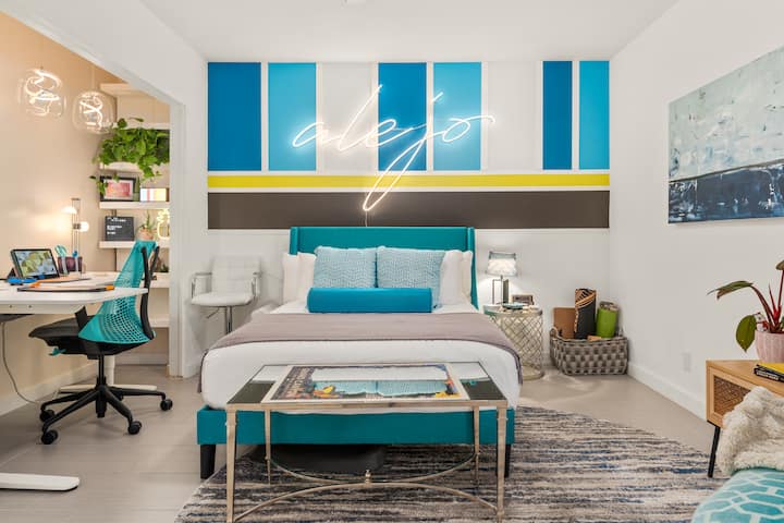 The second bedroom includes a full-sized bed, a dedicated workstation, a clamshell chair for reading, and gear for an at-home workout.