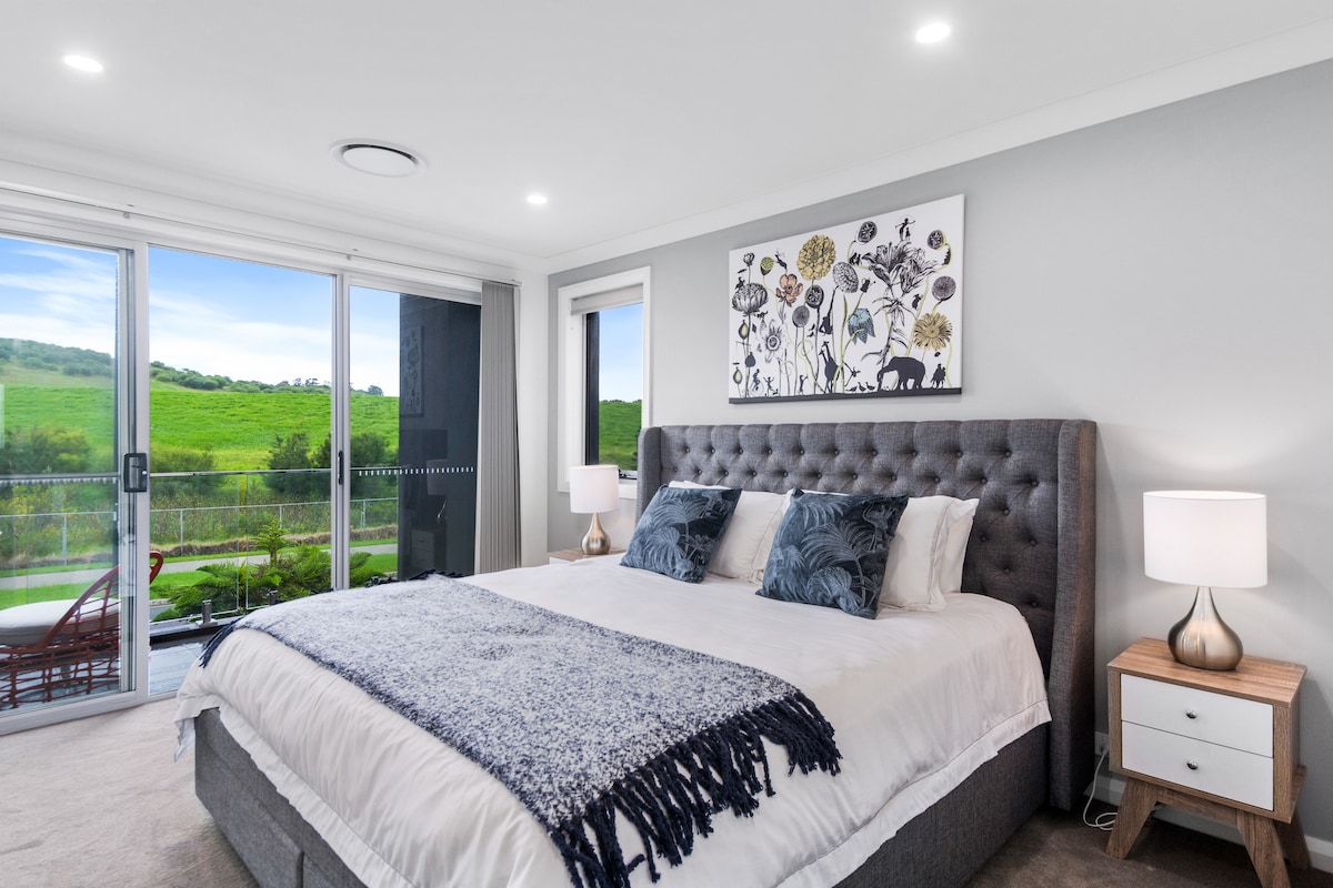 Upstairs, the primary bedroom features a king-size bed and an ensuite, as well as a private balcony with lush, green views. 