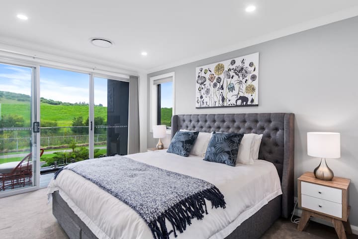 Upstairs, the primary bedroom features a king-size bed and an ensuite, as well as a private balcony with lush, green views. 