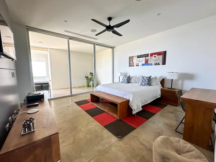 - Encantador dormitorio con una cama doble, con una alfombra decorativa roja y negra para un toque moderno.
- Las puertas correderas de vidrio proporcionan acceso a la terraza, un escritorio de madera y una silla que ofrecen un acogedor espacio de trabajo.
- Los tonos neutros y los elegantes muebles crean un ambiente tranquilo.