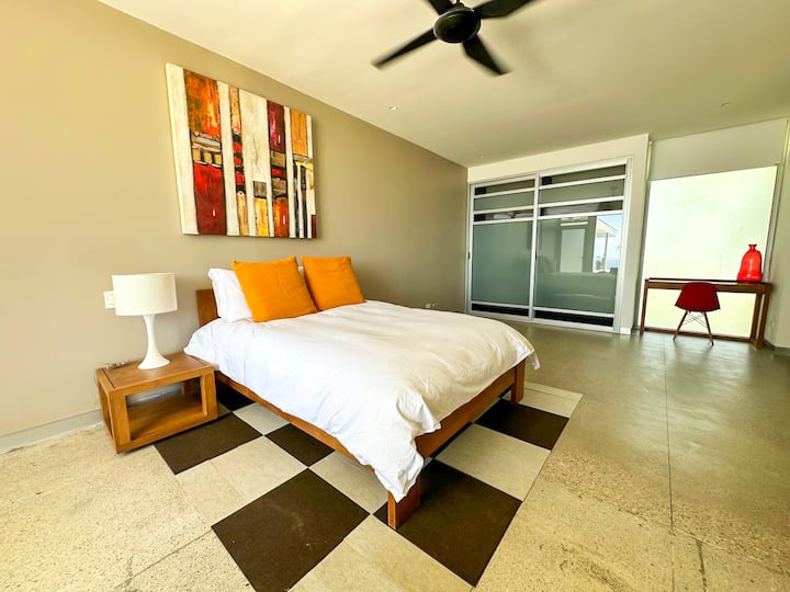 - Habitación luminosa con un piso a cuadros y detalles llamativos y coloridos.
- Diseño cuidado con una cama lujosa y muebles modernos, que crea un ambiente acogedor.
- Grandes puertas correderas se abren hacia un área de estudio privada, lo que proporciona versatilidad y privacidad.