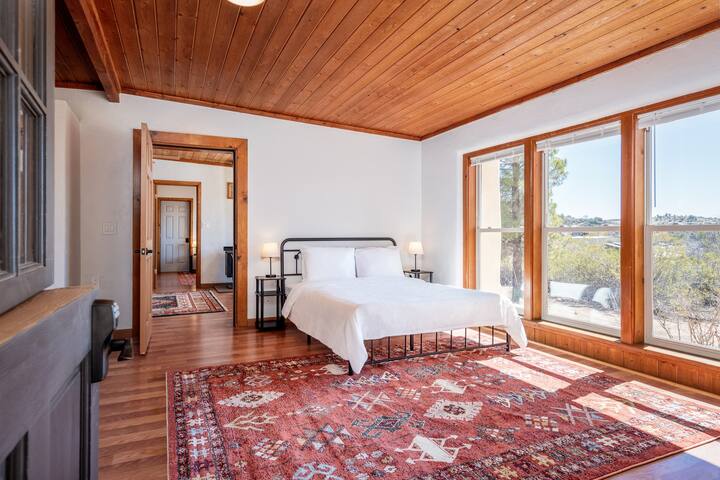 The front bedroom in the guest house features a clean plus cozy Queen bed along with expansive ceiling-to-floor windows along with an en suite bathroom.