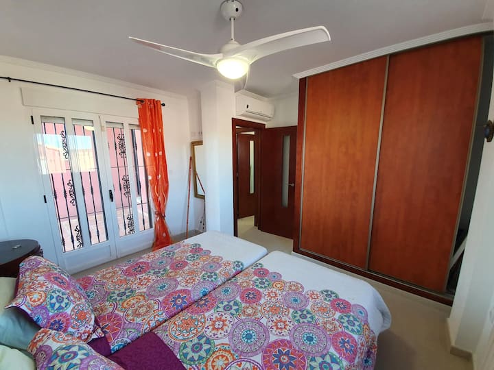 Slaapkamer beneden met dubbel bed met airco, fan, patio deuren naar het privé terras en ingebouwde kasten. (aansluitend badkamer)