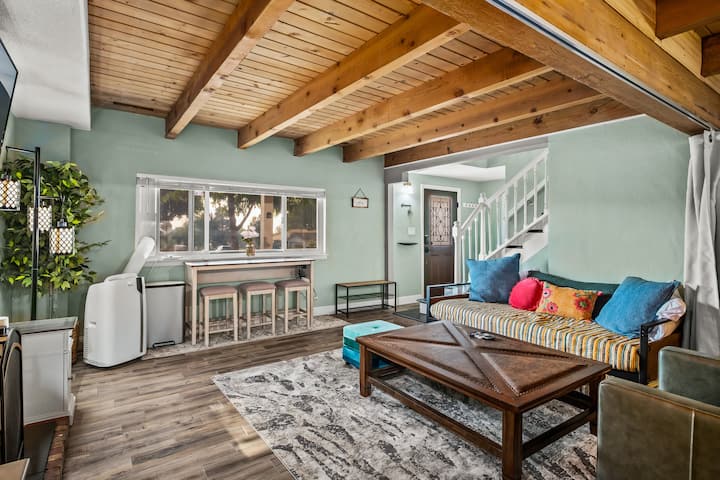 Family Room - Beautiful morning light flows thru the space, set against the warm natural wood beamed ceiling. Work bench seating for 3 with ample outlets. Pop of color daybed couch converts to 2 twin beds. 