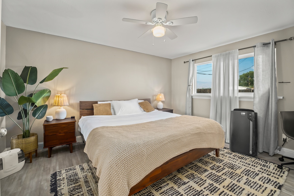 Bedroom #3 - Master suite, king bed (Zinus memory foam), two nightstands with lamps, charging outlet on left nightstand, HomePod Mini, humidifier, luggage rack, and closed door work desk on right side with portable wireless charger. 