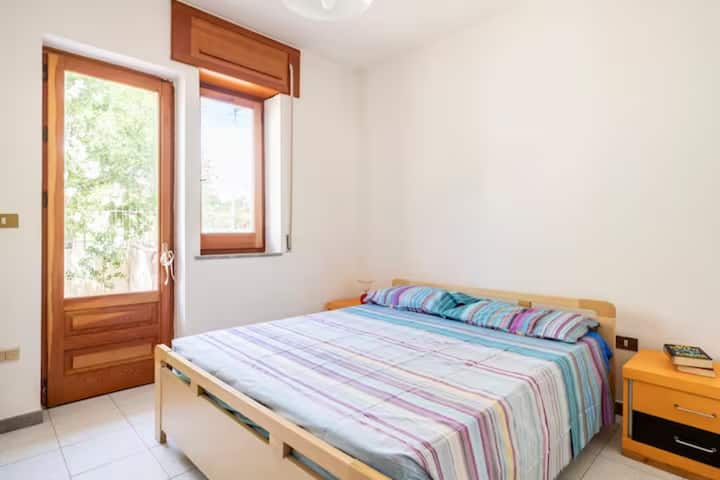 غرفة نوم مزدوجة مع طاولتين بجانب السرير مع مظلات مصباحين مع خزانة ملابس لوضع الملابس وتعليق القمصان والملابس والسترات.