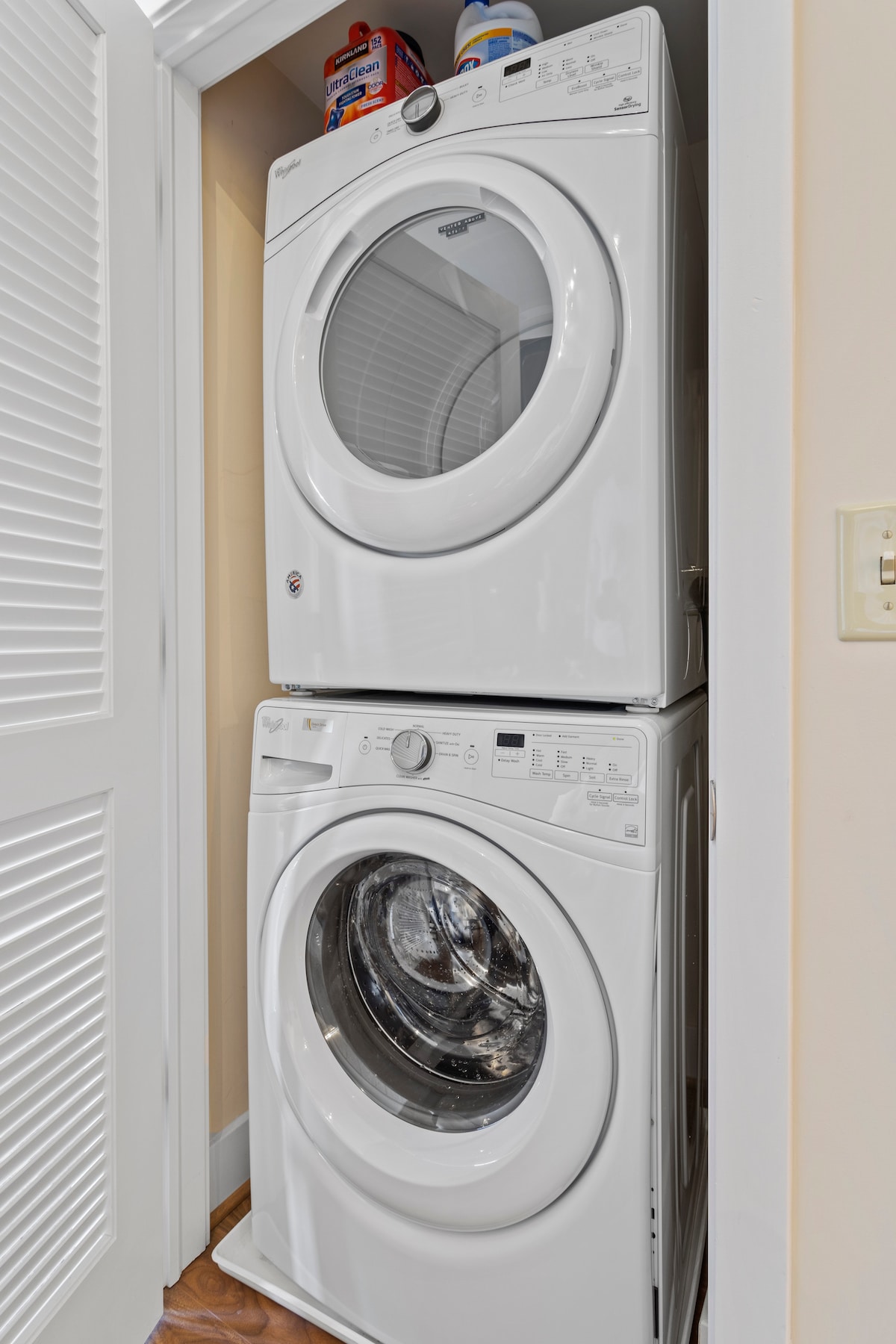 A stacked washer and dryer unit is neatly positioned in an enclosed space. The machines feature a modern design with white finishes. Laundry supplies are visible on top, ensuring convenience for guests during their stay.