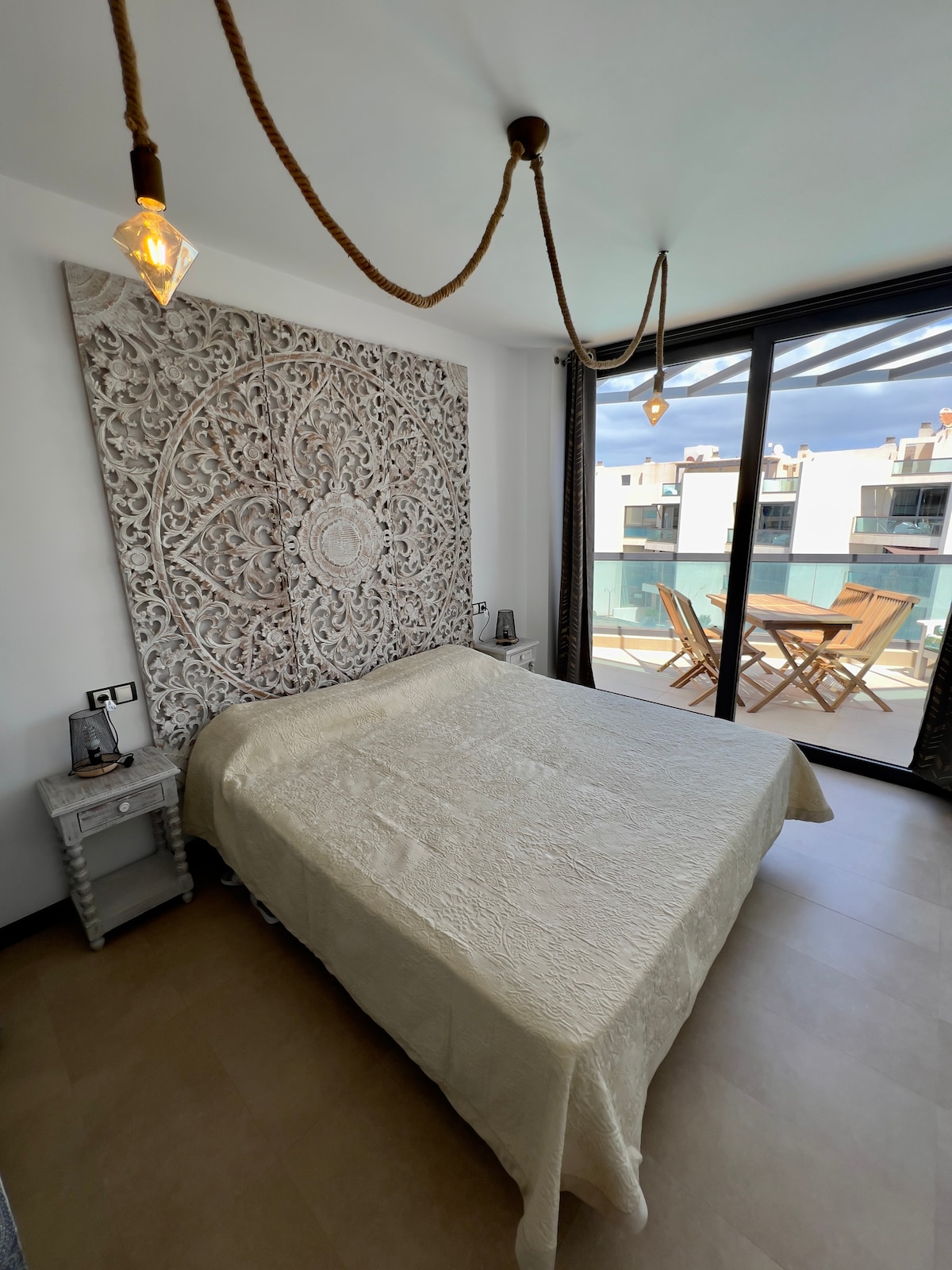 Double bedroom with ethnic furniture and large Mandala to inspire relaxation