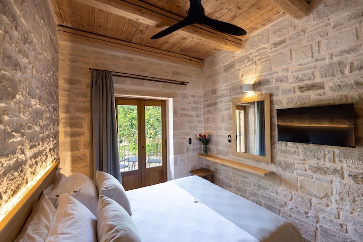 Characterised by the light stone walls found throughout the house, the room is equipped with a king size bed.