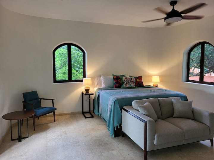 ห้องนอนระดับกลางพร้อมเตียงคิงไซส์โซฟาสำหรับอ่านหนังสือหรือดูทีวีและเก้าอี้สวยๆที่ตอนนี้มีโคมไฟหนังสือด้วย