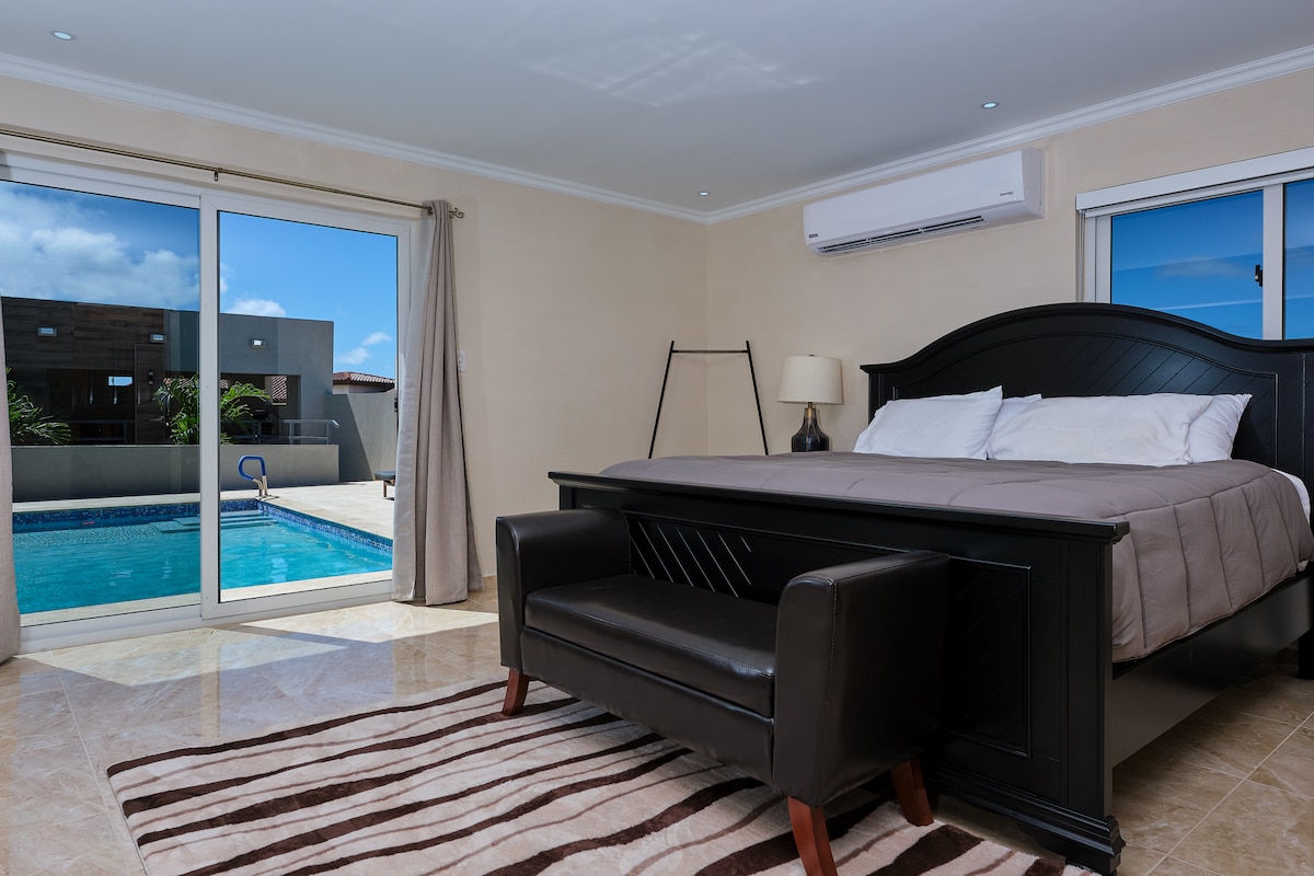 Dormitorio principal con cama tamaño king y acceso a la piscina