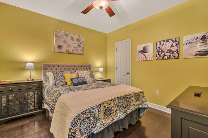 Chumba cha kulala cha malkia chenye bafu la chumbani ambalo linajumuisha beseni la kuogea lenye jeti.  Taa za kando ya kitanda zina bandari za USB.