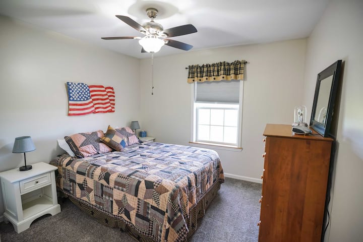 This third bedroom includes a queen bed, two nightstands, a dresser, and a closet for all your belongings during your stay. The bedroom is located on the front side of the house, with a scenic view out the window.