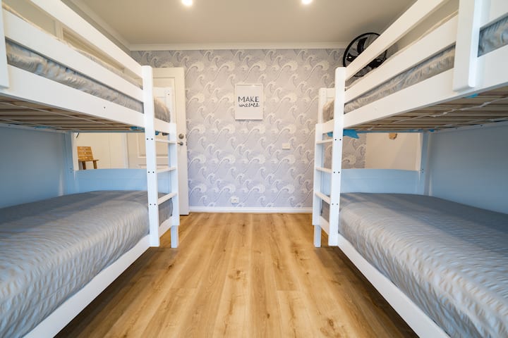 Chumba cha kulala 3 (Mawimbi ya Bahari): Mawimbi ya bahari ya kufurahisha yaliyo na seti 2 za vitanda vya ghorofa na feni ya ukuta ili kupata hewa baridi wakati wa kiangazi. Vitambaa vya kitanda na taulo za bila malipo hutolewa kwa kila kitanda cha mgeni.