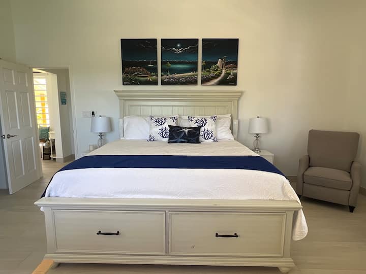 Master bedroom with King bed , 2 nightstands with lamps and reclining chair.