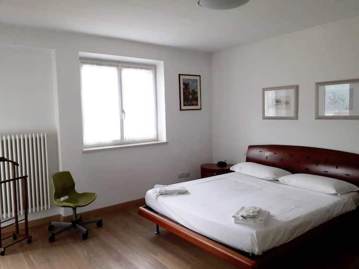 dhoma e parë e gjumit fotografuar gjatë ditës  për të lejuar dritën natyrale të hyjë nga dritarja dhe dera e vetë dhomës. Në këtë fotografi mund të shohësh tavolinat pranë krevatit në pozicion të përkryer. 