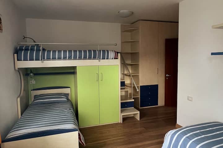 dhomë argëtuese me tre krevate për fëmijë me dollapë të mëdhenj