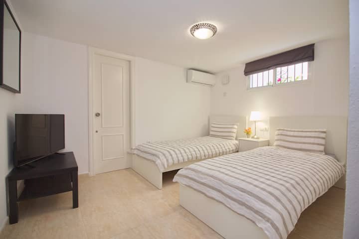 Second Bedroom Featuring Two Single Beds with Air-Con, Wardrobes for Storage & Large Screen TV.