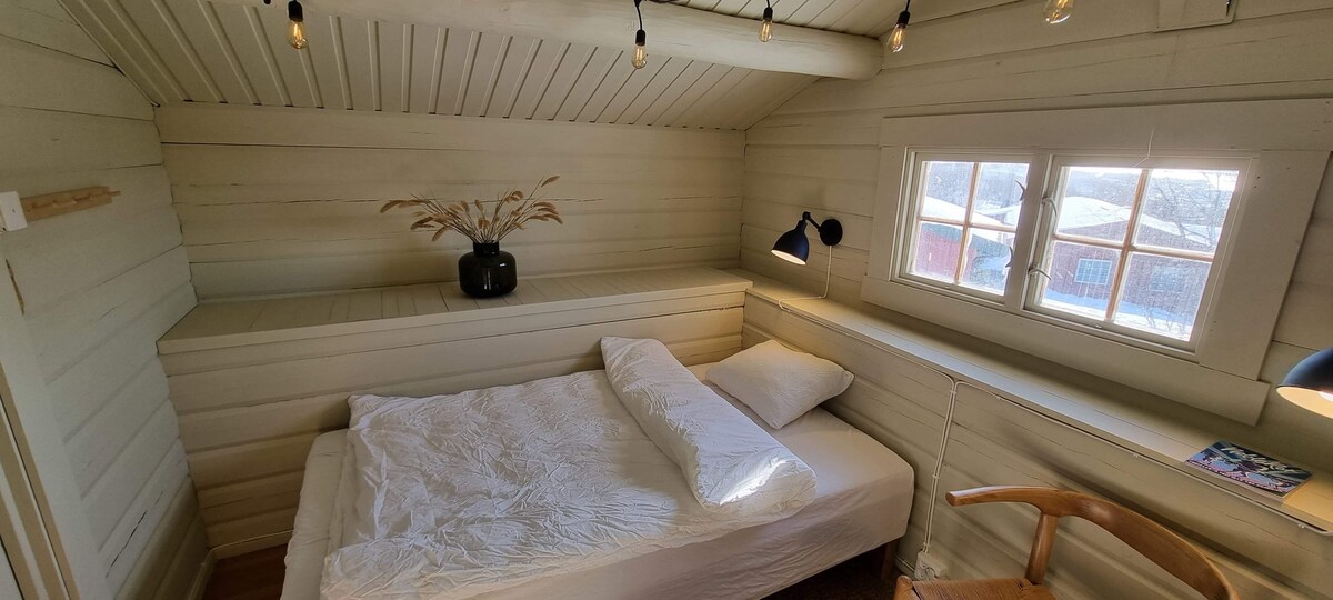 Cama doble (120x200cm) en la casa de huéspedes con ganchos y mucho espacio para el equipaje en los estantes de la pared.