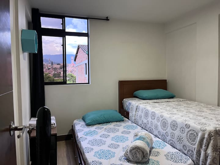 Chambre secondaire avec deux lits simples (lit plat), placard et vue sur la ville.