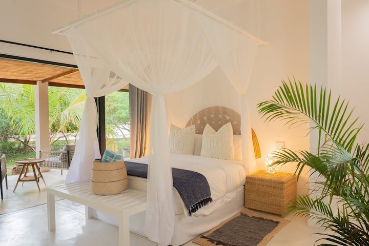 El dormitorio principal.
Las puertas correderas conducen a la terraza que se extiende por toda la parte delantera de la casa frente al mar. Fuera de la vista, pero a la derecha, está el baño privado. 