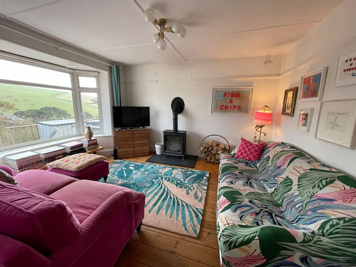 Удобна дневна соба / ТВ соба со рингла на дрва. Оваа соба може да се користи и како спална соба, бидејќи розовиот кауч е двоен кауч на спуштање.