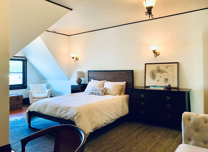Primärt sovrum med premium queen-madrass, stor byrå, arbetsyta med skrivbord, soffa och sittplatser för fönster