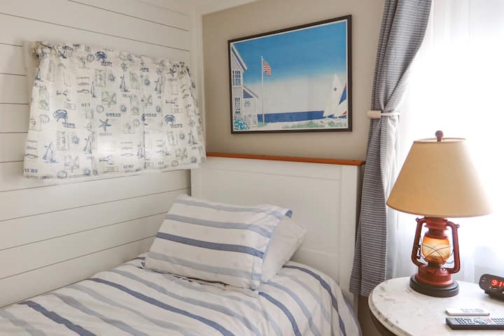 Cama individual en el dormitorio en el primer piso.  Esta habitación es perfecta para cualquier persona que no pueda subir escaleras.  El medio baño está al otro lado del pasillo y la ducha exterior está en la terraza.
