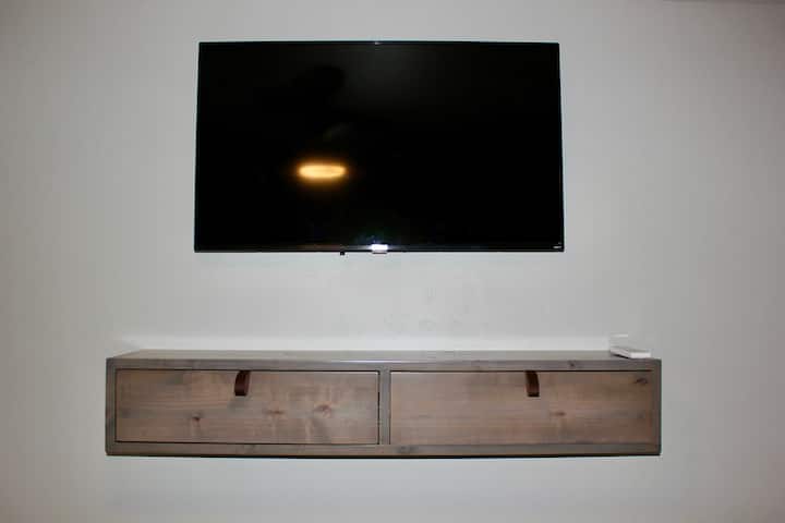 Roku e TV satellitare con mobili da parete realizzati localmente. 