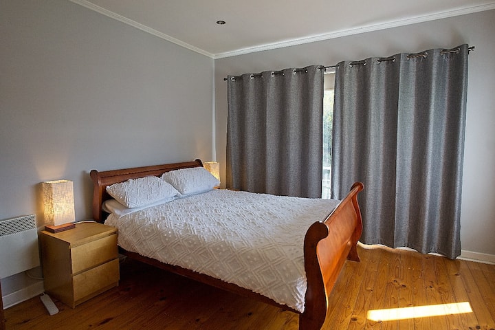 Chumba kikuu cha kulala kilicho na mapazia meusi na vipofu.