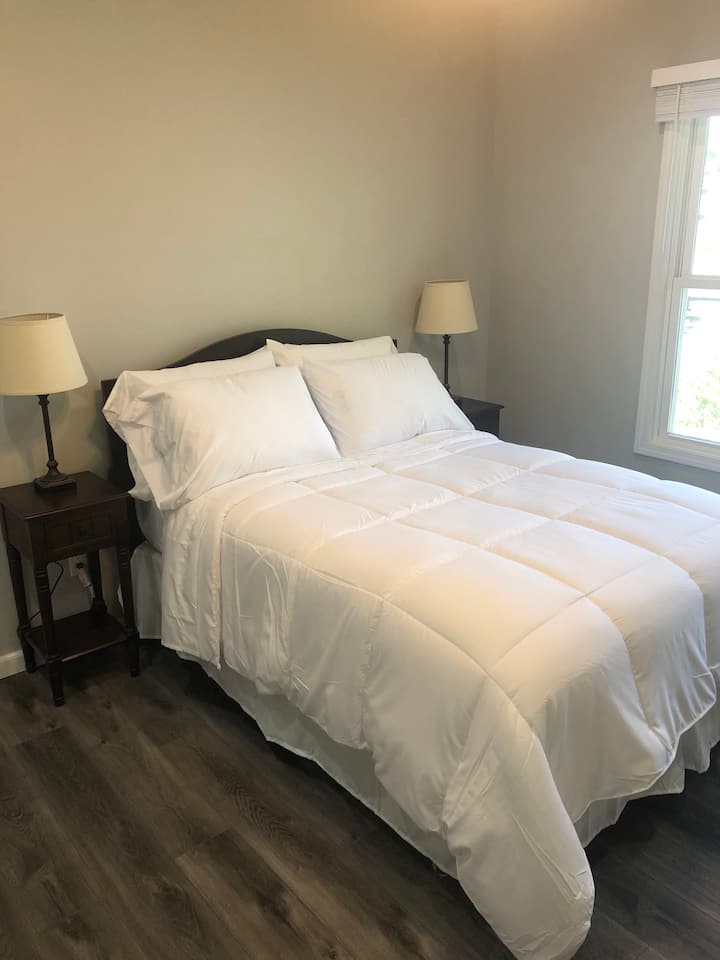 Dhomë gjumi në katin e dytë me krevat me madhësi të plotë, komodinë, dollap dhe televizor.