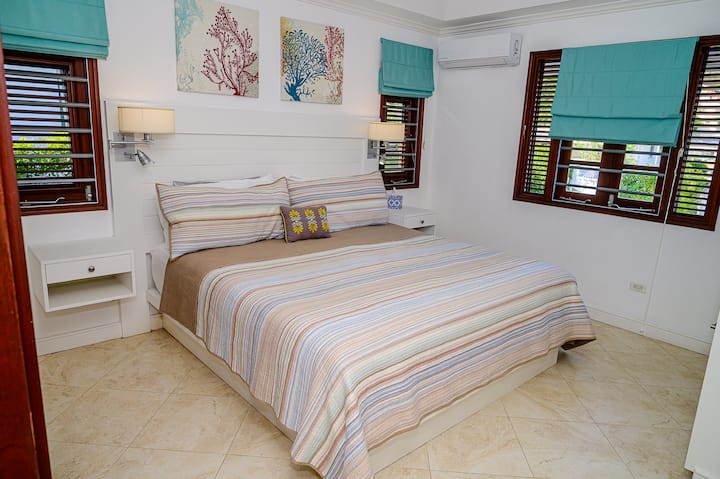 Chambre principale avec salle de bains privative, lit King  Size, climatisation et ventilateurs de plafond avec un grand espace de placard.