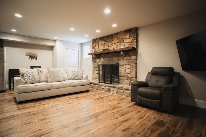 楼下起居区配有沙发床、65英寸智能电视、燃气壁炉、冰箱和水槽。 