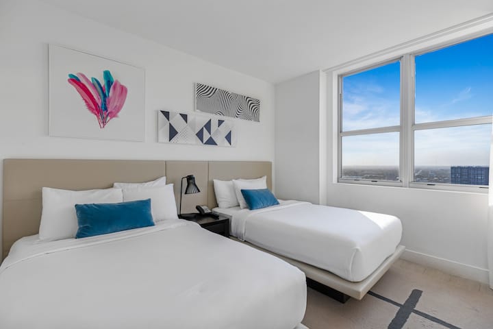 Vstúpte do prvej spálne, kde dve pohodlné manželské postele vytvárajú ideálne prostredie pre rodiny alebo skupiny. Je jasná a vzdušná s prirodzeným svetlom a moderným dekorom a ponúka priestor na pokojné noci.