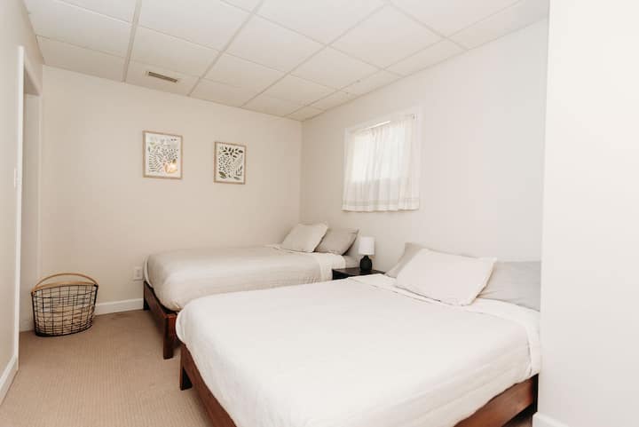 Dormitorio en el sótano con ventana y espacio en el armario. Dos camas completas con ropa de cama Hearth y de mano.
