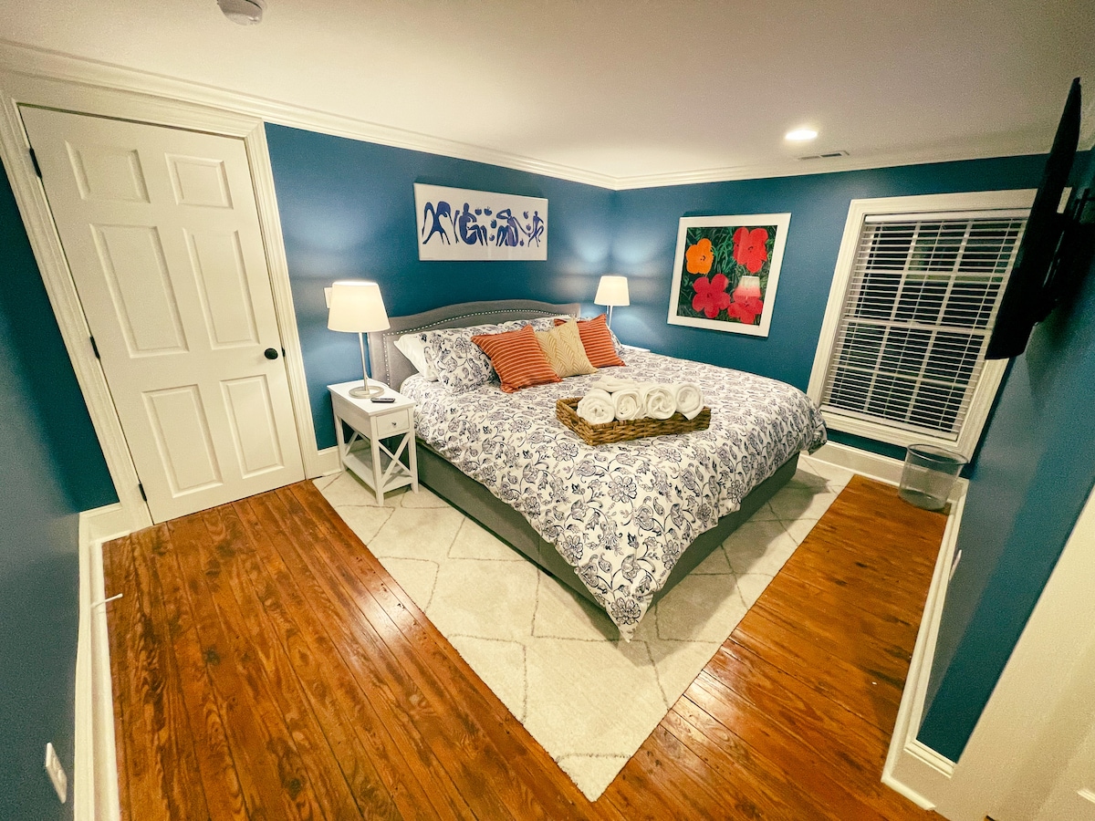 Bedroom 2 includes a KING bed, en-suite bath, privacy shade, and wardrobe closet with built in dresser. Other amenities include a 55" smart TV, Google Nest smart speaker, and bedside lamps with built in USB cords (USB C, micro USB, and Apple). 