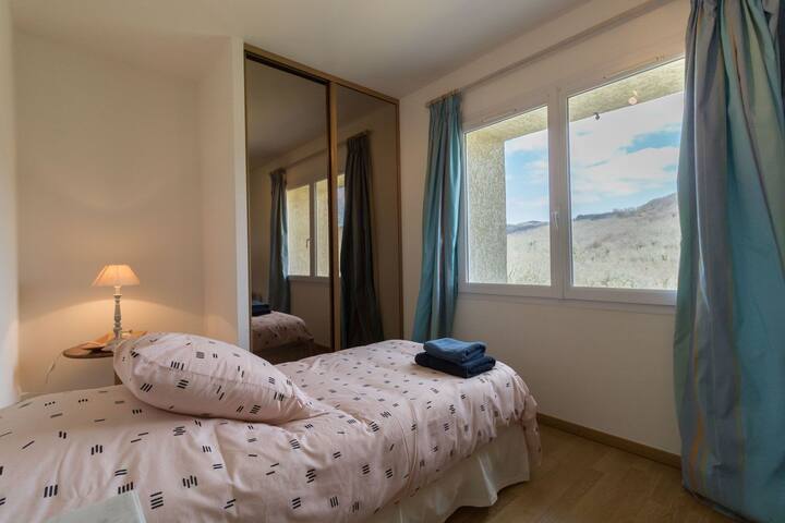 2e chambre individuelle avec une vue sur le paysage vallonné du domaine.