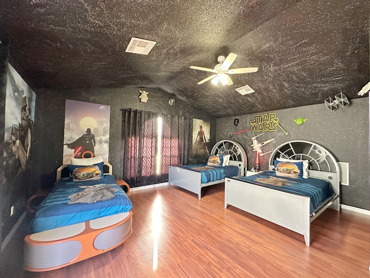 ทุกคืนจะเหมือนอยู่ในอวกาศ: ผนังและเพดานเป็นภาพดาราจักรวาลสีเข้ม มีเตียงคู่หัวเป็นรูปเครื่องบิน X-Wing พร้อมผ้านวมสไตล์กรูกู ไม้ดาบนีออนและงานศิลปะของเรย์ช่วยเติมเต็มการหลบหนีจากสตาร์วอร์สครั้งยิ่งใหญ่นี้               