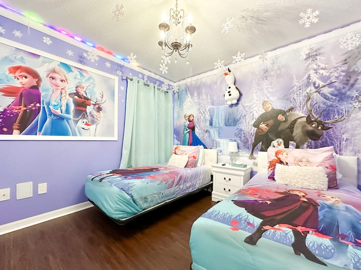 Ingia katika nchi ya ajabu iliyogandishwa: vitanda viwili vilivyopambwa katika duvets za Elsa&Anna, decals za theluji zinazong 'aa juu, chandelier ya kioo inayong' aa, trim ya bluu ya barafu inayoonyesha kuta za bluu ya anga, na ukuta wa Arendelle unaofagia-hali ambapo kila usiku unakuwa mazingaombwe safi