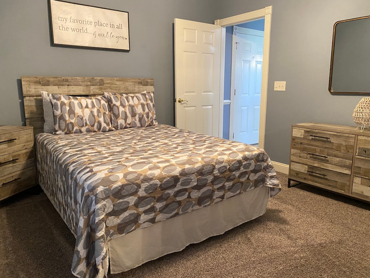 Chumba chenye nafasi kubwa na kitanda na televisheni.  Chumba hiki kiko mbele ya nyumba, kinatoa nafasi ya ziada kwenye chumba na kabati.