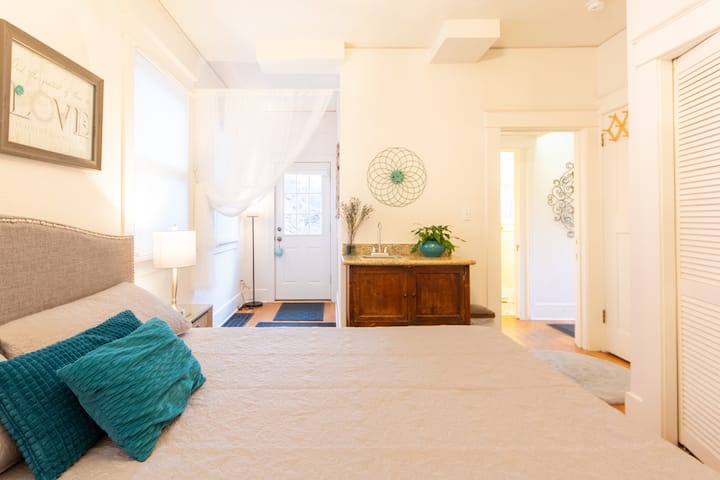 The view from the couch in first floor king bedroom suite to the private back entrance onto the grotto lounge area. Closet space, personal sink, free standing AC & heater. Across the hall is the 3/4 bath, continue down the hall to reach the kitchen. 