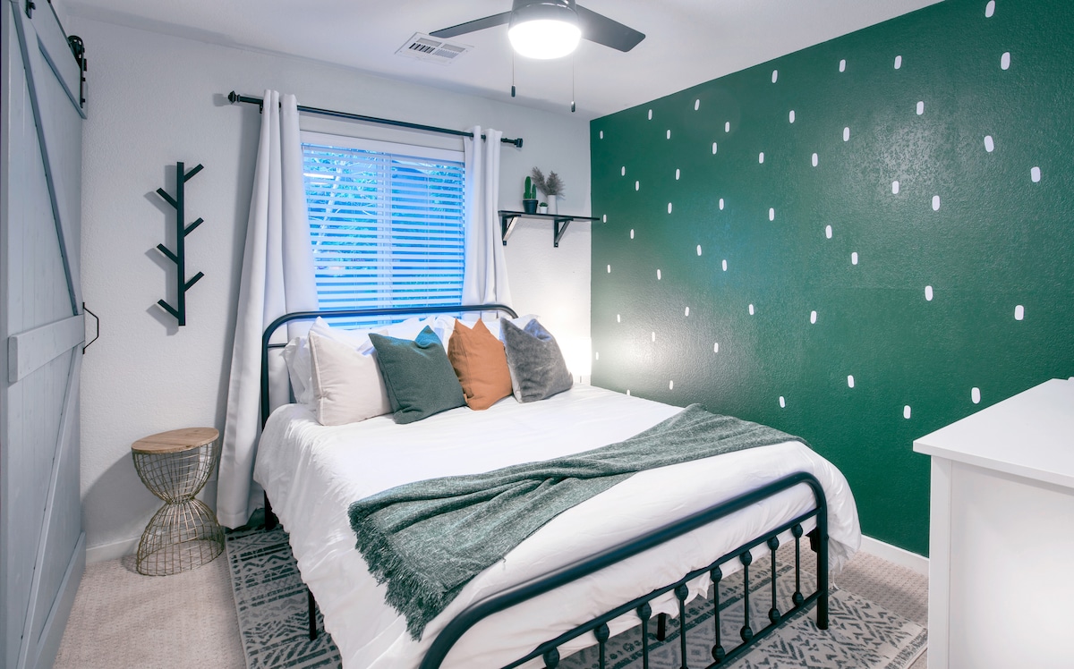 The green bedroom boasts a high-end memory foam queen-sized mattress and bed, amazon echo and a 50" Smart TV.