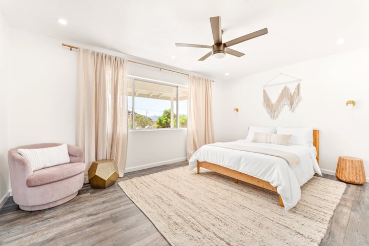 Front Queen bedroom with quality linens, reading chair, dresser, closet for hanging garments and wall-mounted dressing mirror