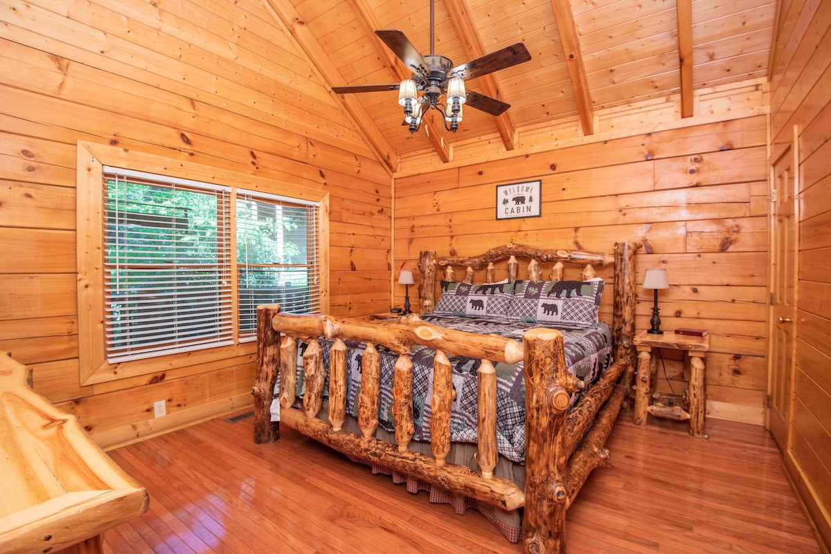 Acogedora habitación de cabaña de madera con cama tamaño king rústica hecha a mano, techos abovedados de madera y vistas tranquilas al bosque, perfecta para un retiro tranquilo en la montaña.