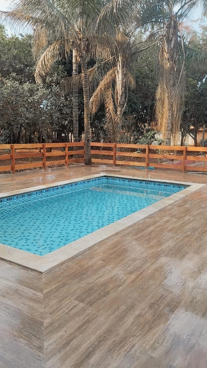 A private pool is framed by a wooden deck, surrounded by lush greenery. The pool's clear water features a textured tile bottom, while the natural light enhances the tranquil outdoor setting.