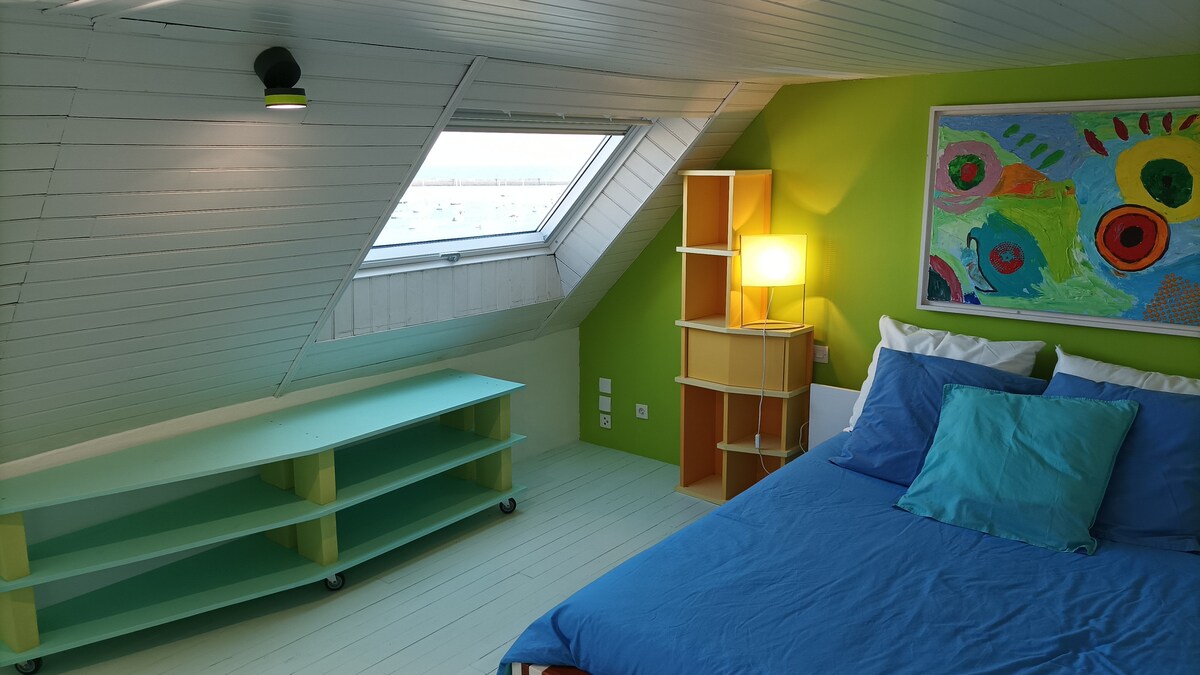 krevet na drugom katu spavaće sobe i velux te pogled na  sidrene brodove