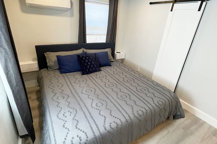 Bedroom with king sized bed, dedicated mini split heating and cooling unit, and black out curtains for sleeping in!