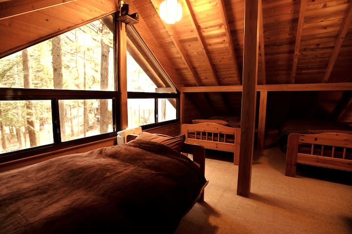 寝室はロフトにベッドを3台、和室リビングに布団を３セットご用意しています。窓の外は森です。